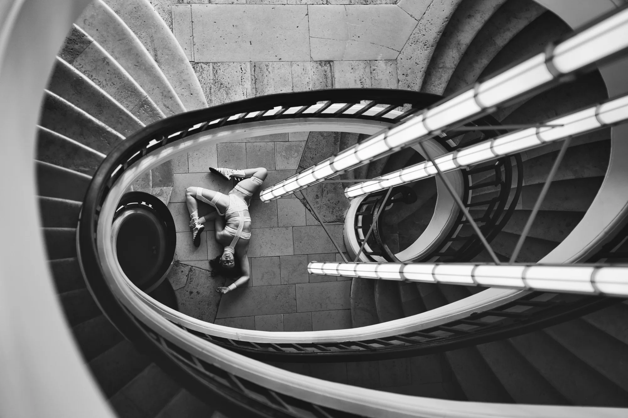 Vue plongeante sur un escalier en colimaçon à Paris, une danseuse allongée au sol, direction artistique HENLAW Paris